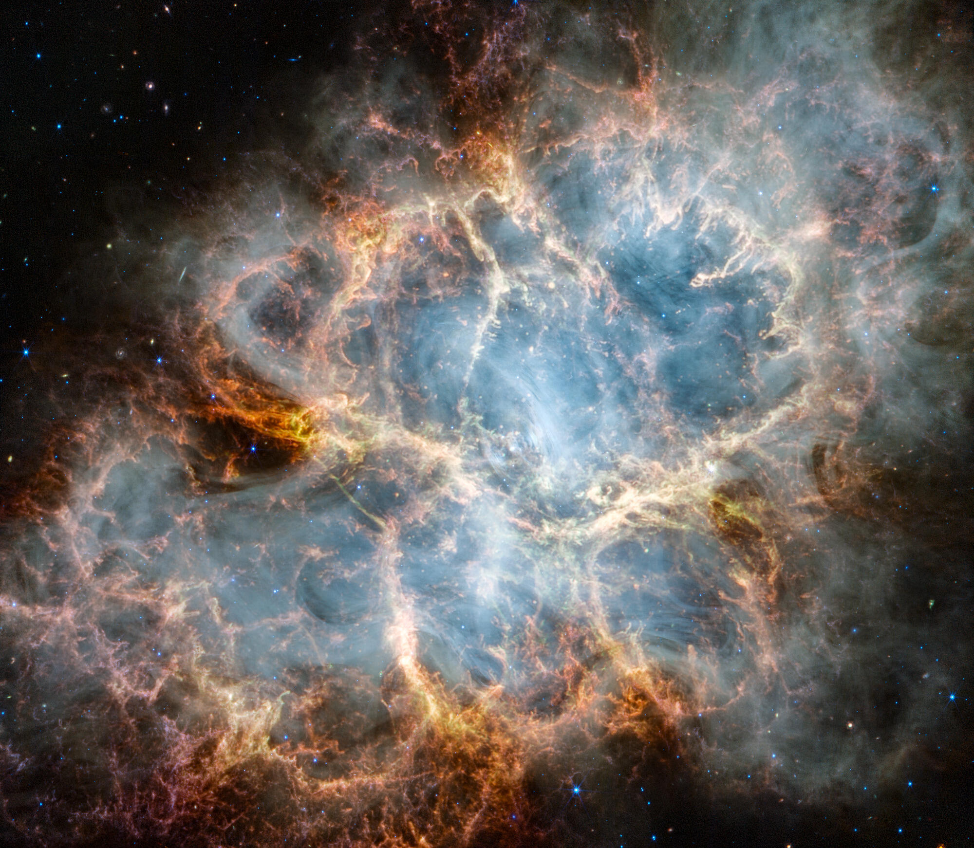 The Crab Nebula A vibrant infrared image of the Crab Nebula supernova remnant. A crisp, cage-like structure of fluffy red-orange gas filaments surrounds a ghostly, translucent white interior of synchrotron radiation. At the very center, a tiny, bright white dot marks the